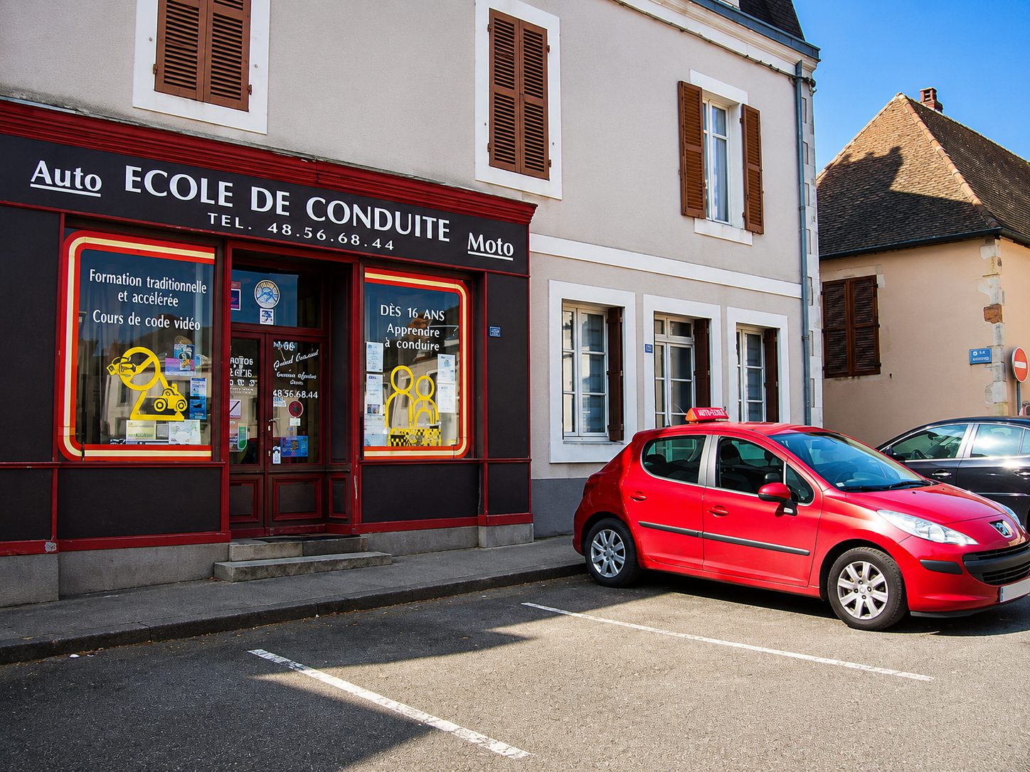La devanture de l'auto-école avec les voitures école garées devant